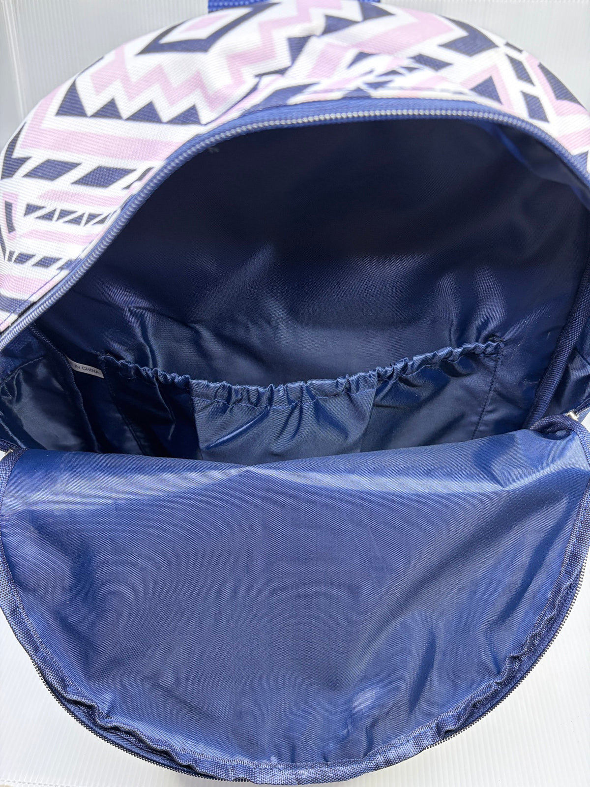 Main compartment interior of the Ivory Ella backpack showing navy lining and elastic-top slip pocket