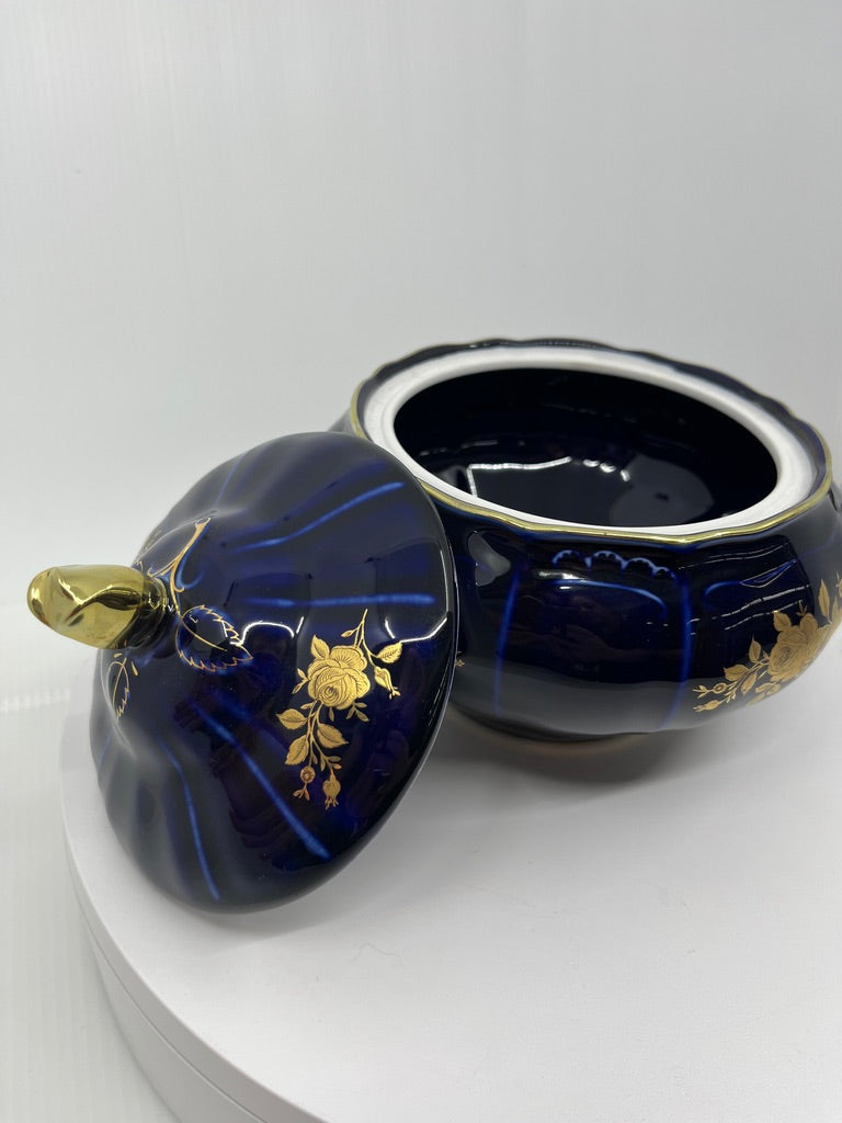 Decorative blue container with lid and hand painted gold floral accents on a white background