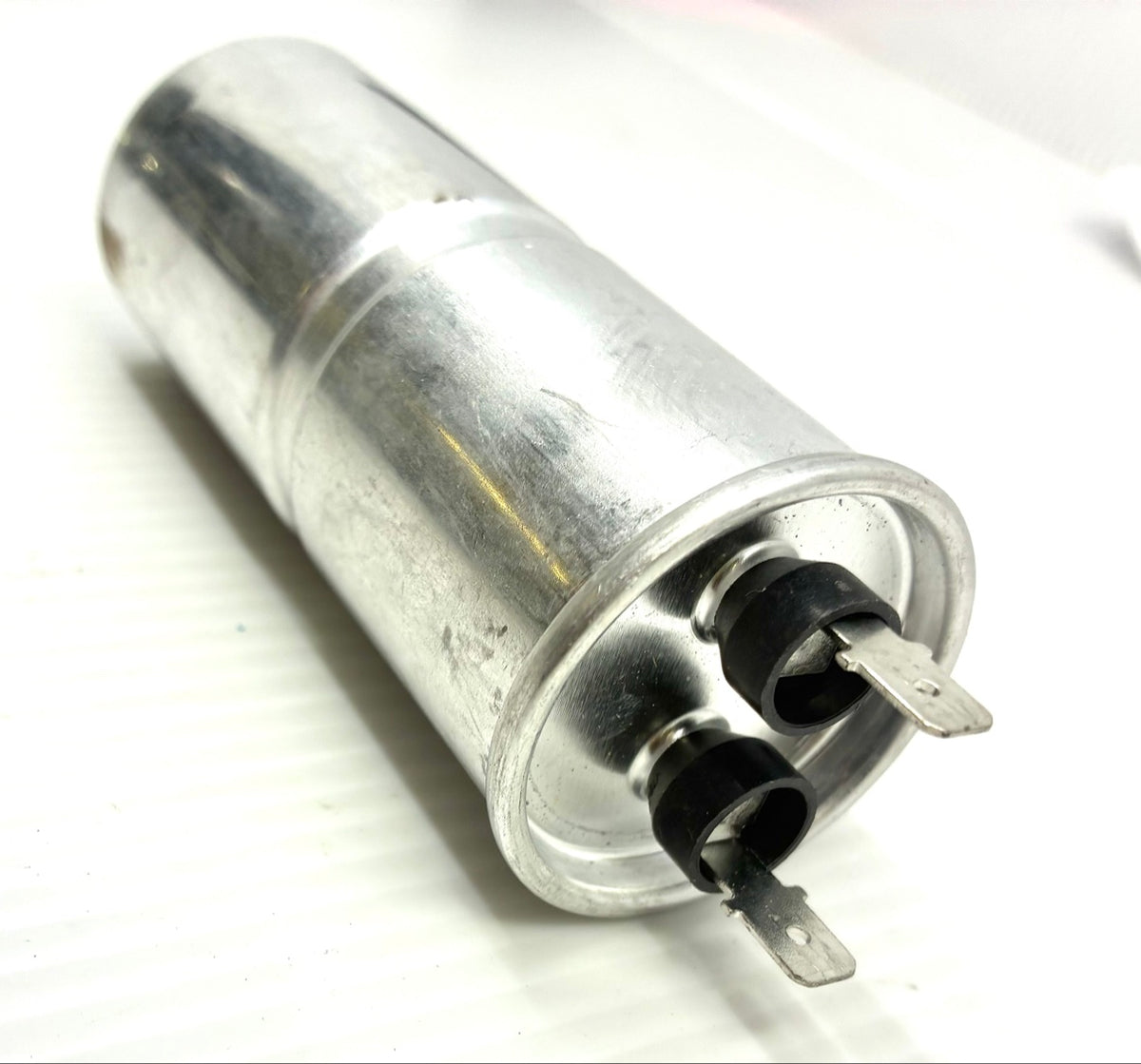 Globe 60uF washer run capacitor aluminum can side view showing spade terminals with black insulating caps