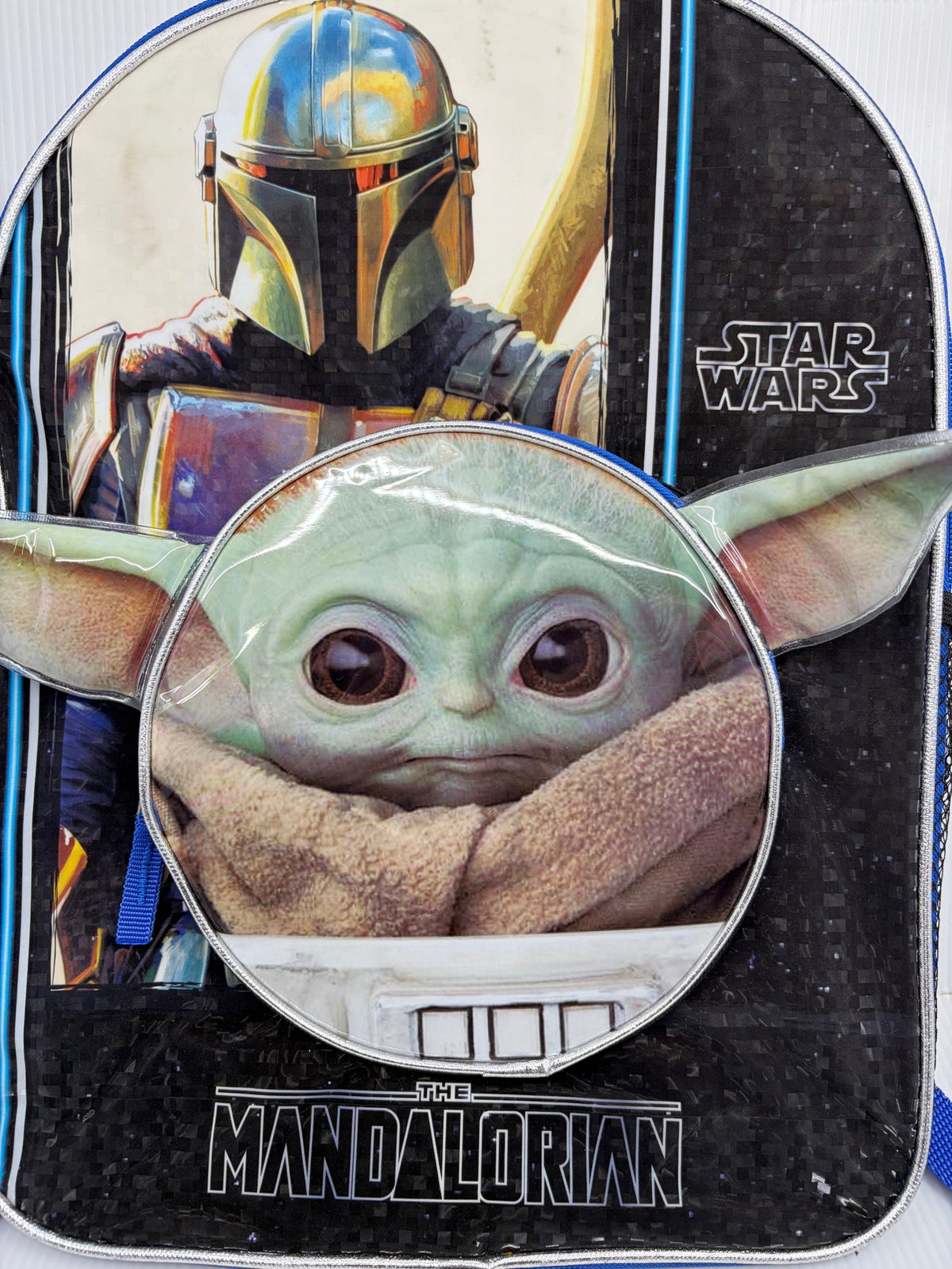 Star Wars Mandalorian backpack close-up front view showing Mandalorian helmet art and Grogu face front pocket with 3D ears
