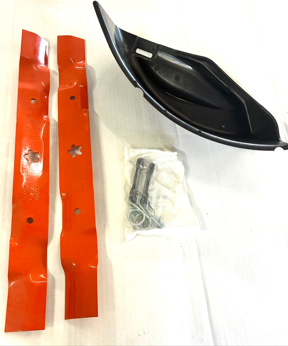 Husqvarna mulching kit components laid out - blades, discharge cover and sealed hardware