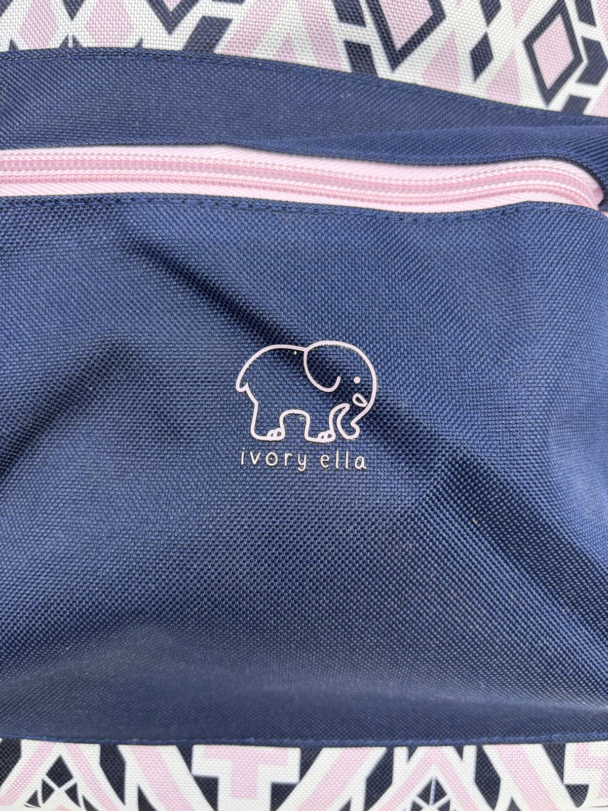 Close-up of the white Ivory Ella elephant logo on the navy front zip pocket with pink zipper