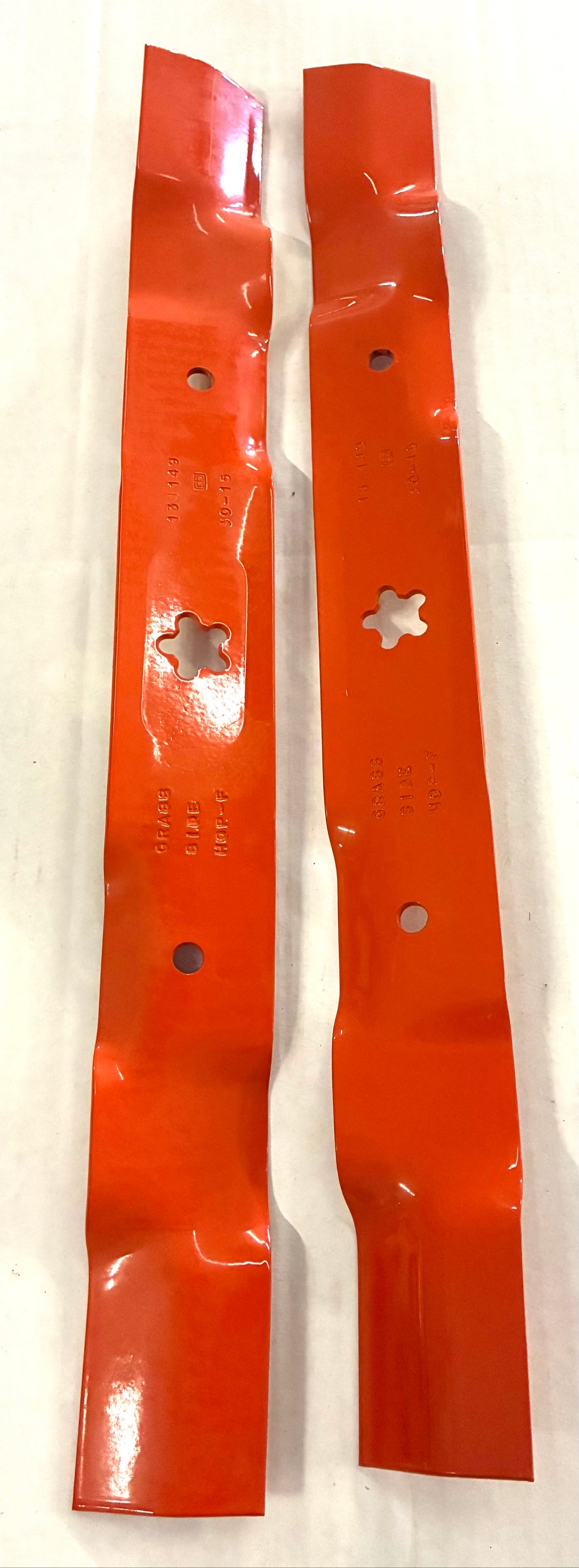 Close-up of Husqvarna 532134149 mulching blades showing 134149 and GRASS SIDE stampings and 5-point star center hole