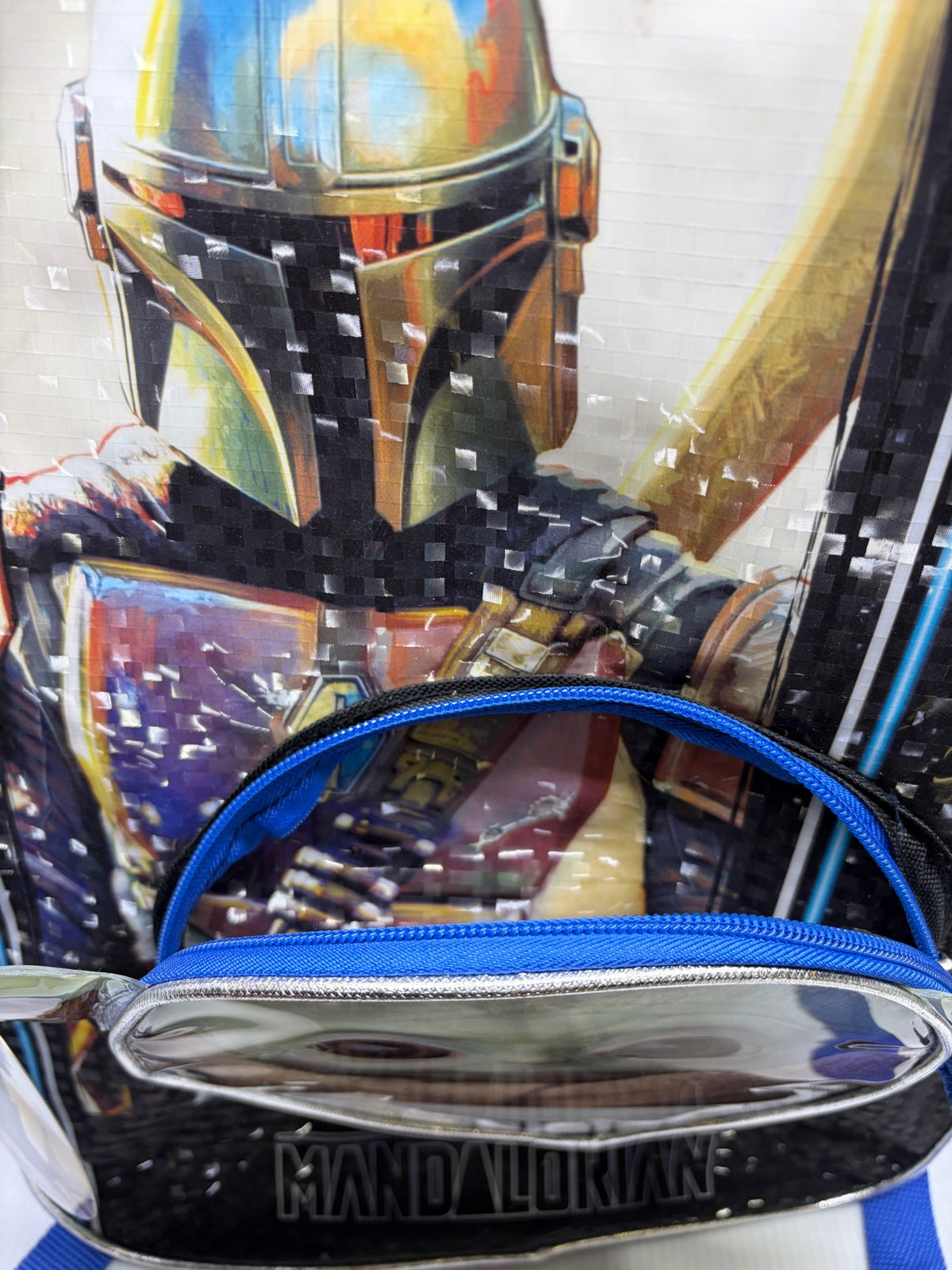 Top view of the Grogu front pocket zipper and Mandalorian helmet art detail on the backpack