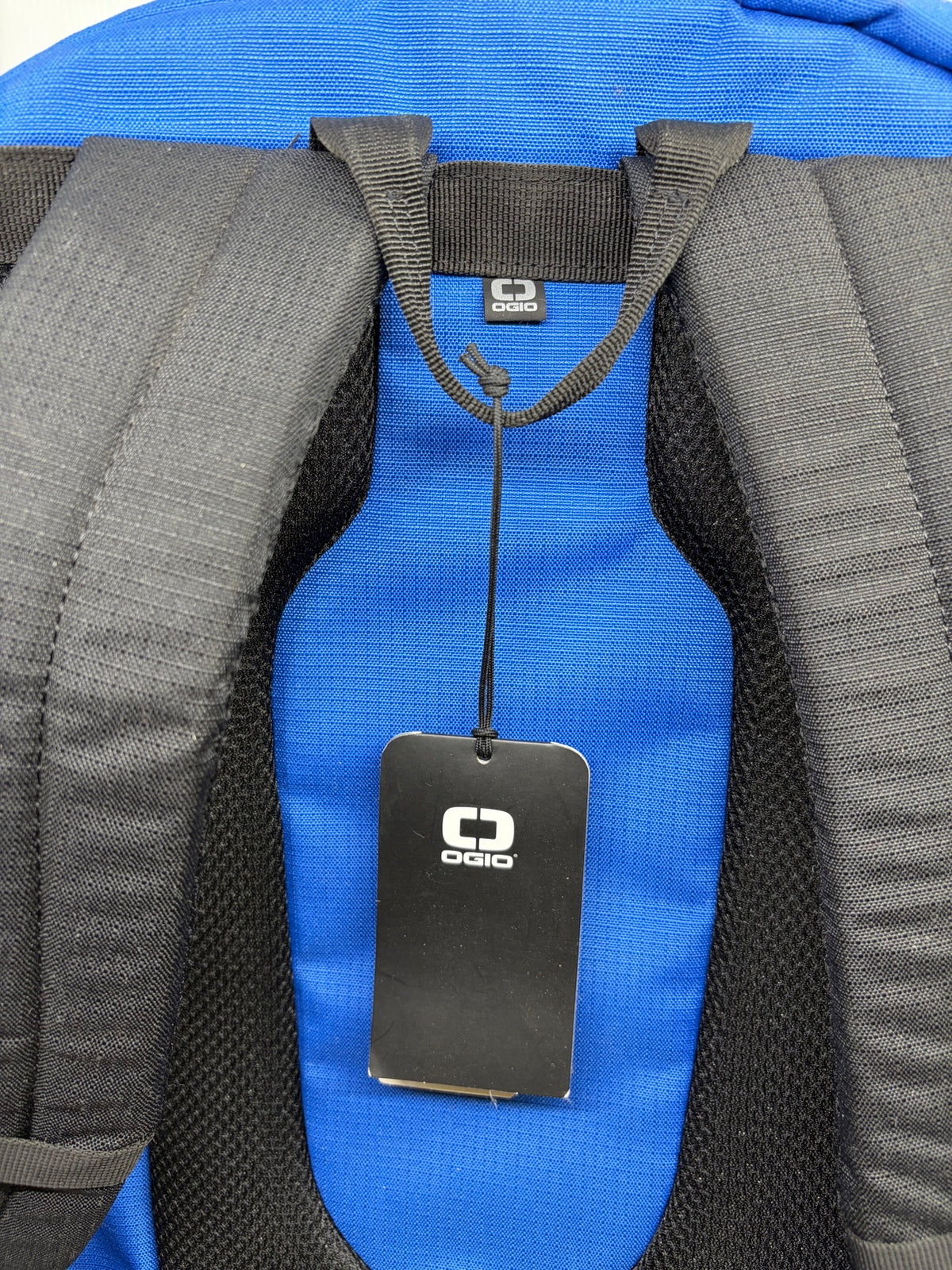 Close-up of the back panel, top grab loop and OGIO hangtag on the blue Shadow backpack
