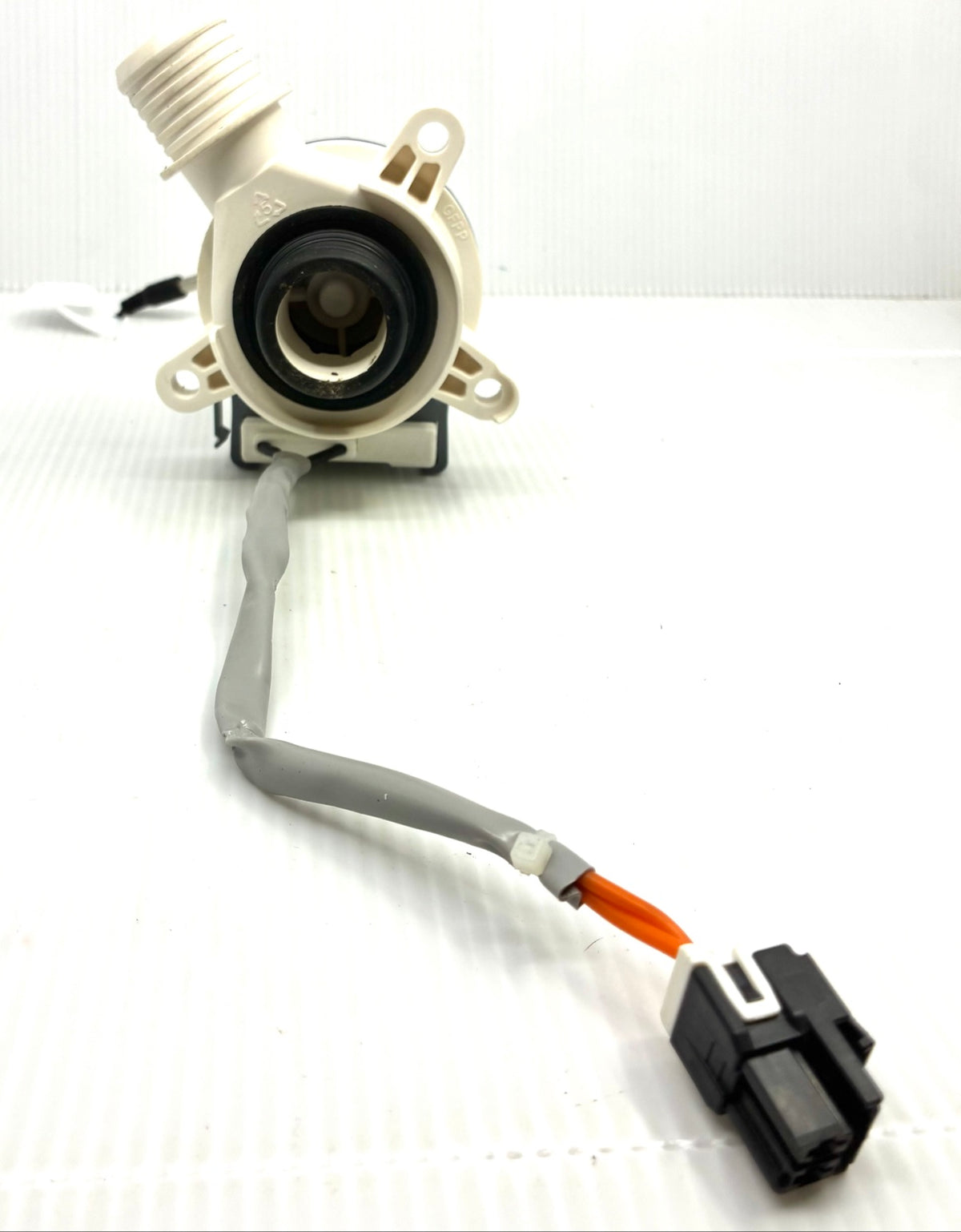 Front view of washer drain pump inlet and impeller opening with mounting ears and harness connector in foreground