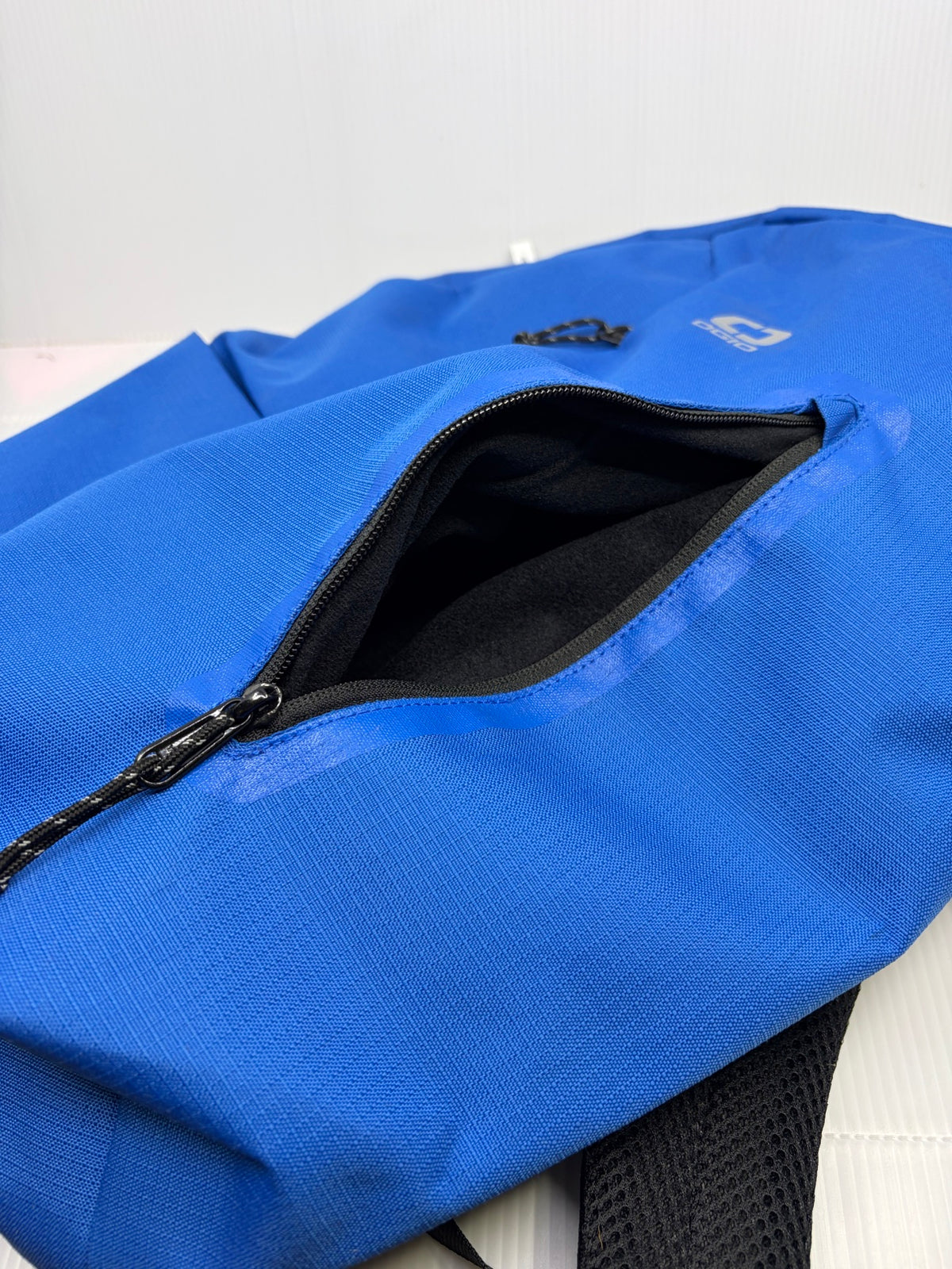 Fleece-lined front vertical zip pocket open on the OGIO Shadow backpack, showing black fleece interior