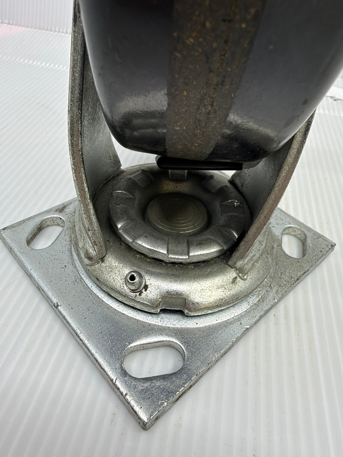 Underside of Faultless swivel caster top plate showing slotted bolt holes, swivel race and grease zerk