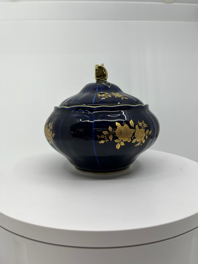 Navy blue ceramic pot with gold floral patterns on a white surface