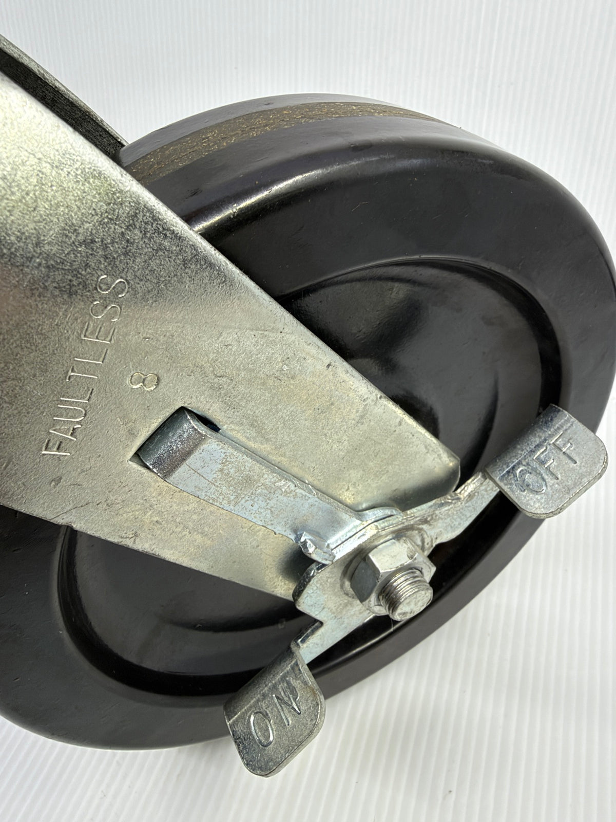 Close-up of Faultless caster brake pedals stamped ON and OFF on axle-mounted brake arm
