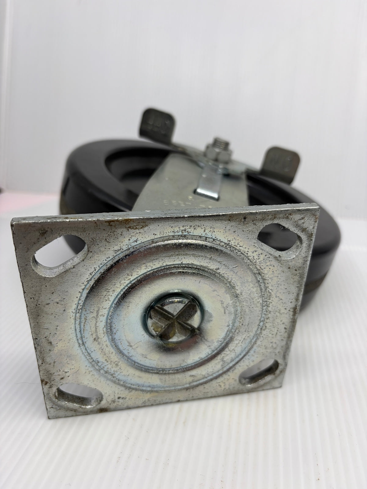 Bottom of Faultless caster top plate showing kingpin and four slotted mounting holes