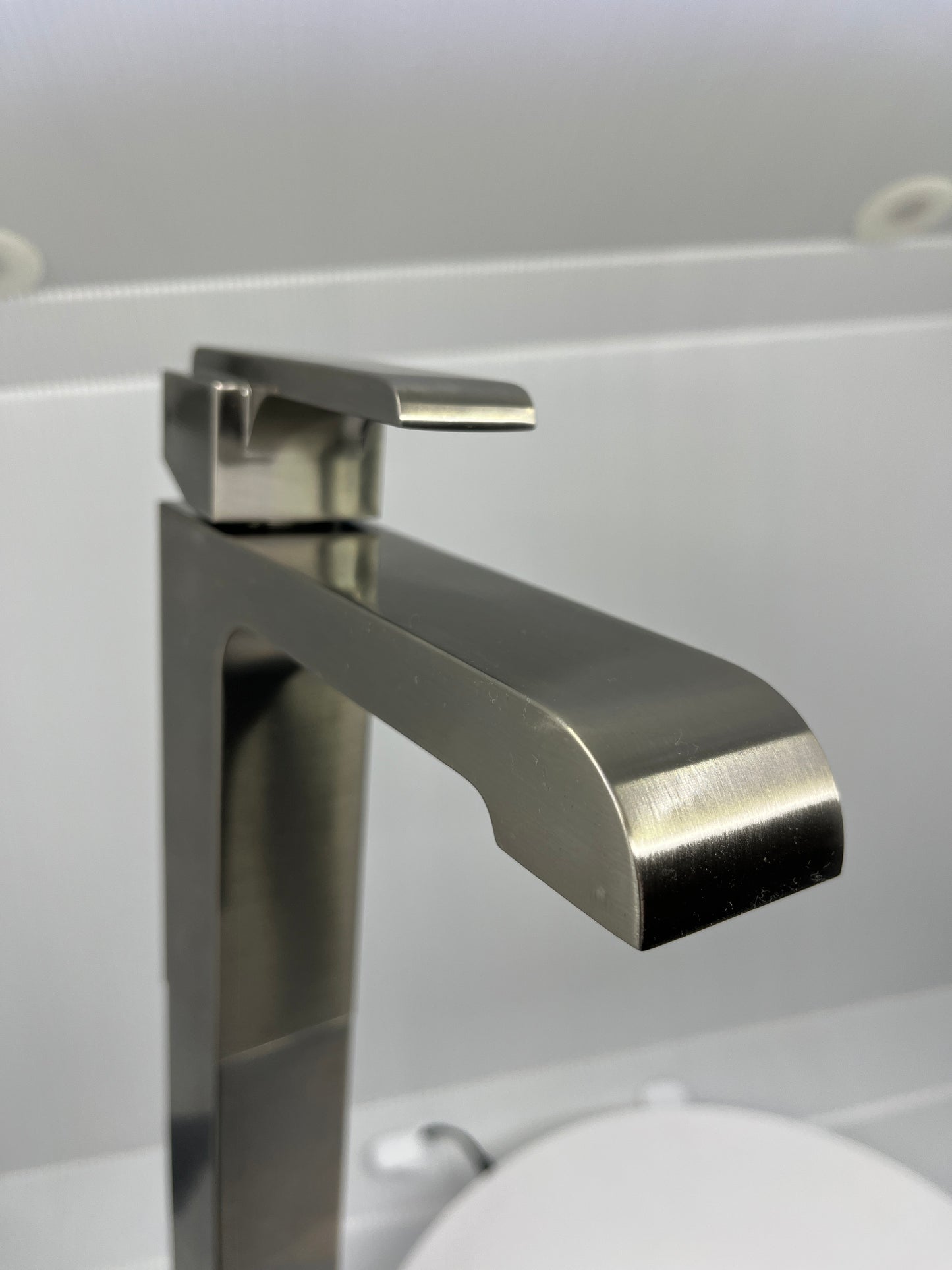 Close-up of stainless steel single handle faucet on a white background.
