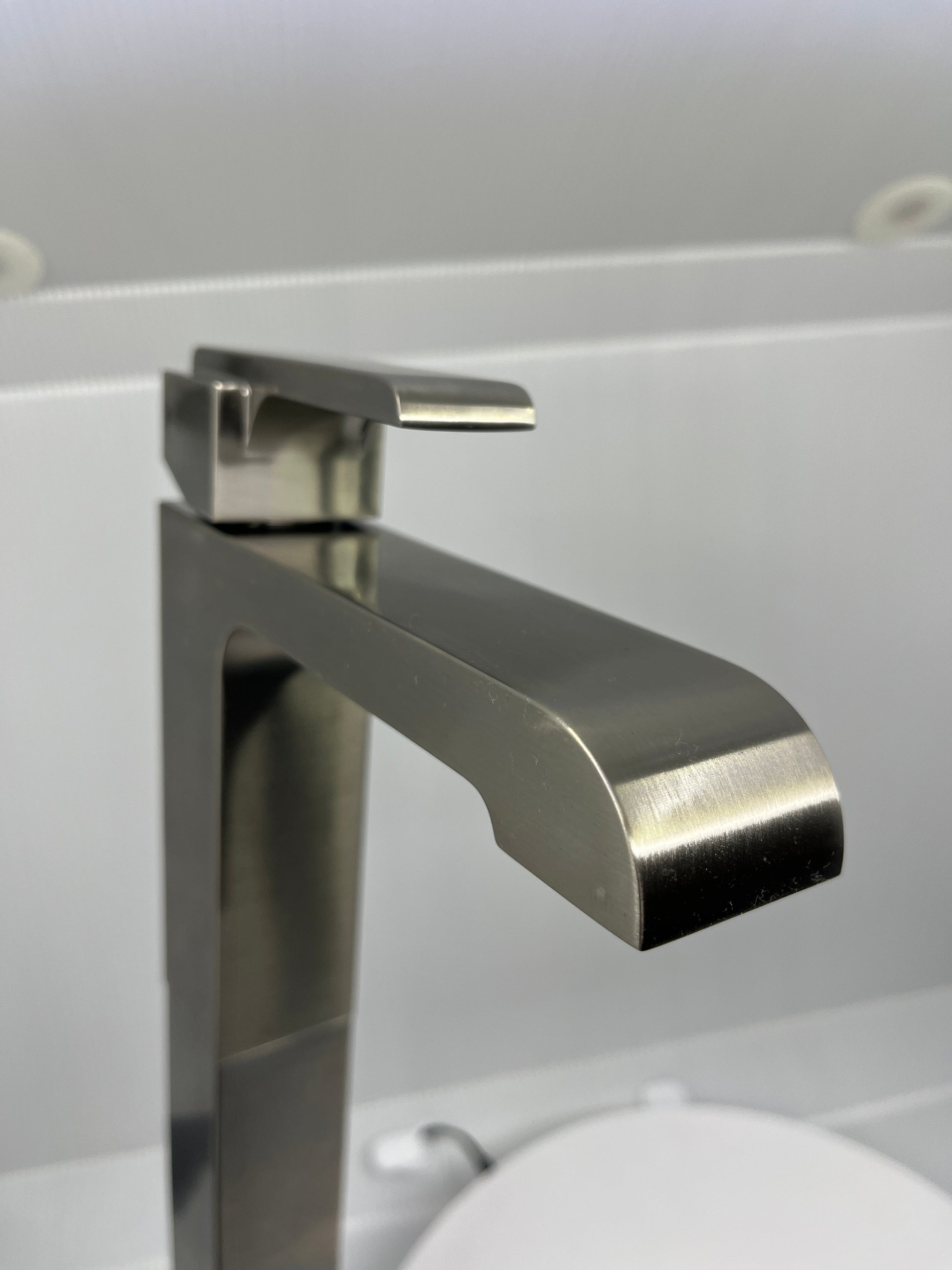 Close-up of stainless steel single handle faucet on a white background.