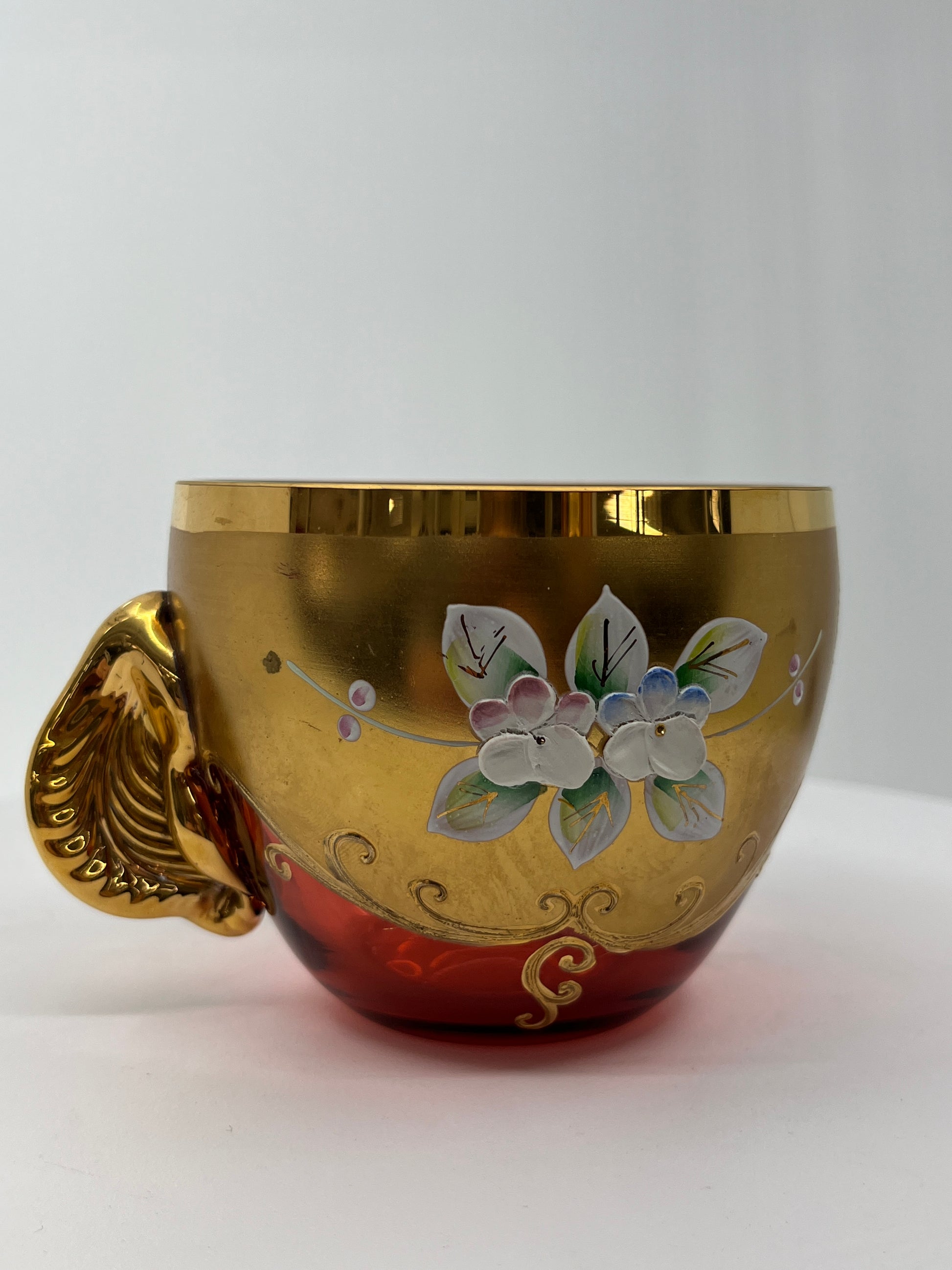 Decorative glass cup with floral design and gold accents on a white background