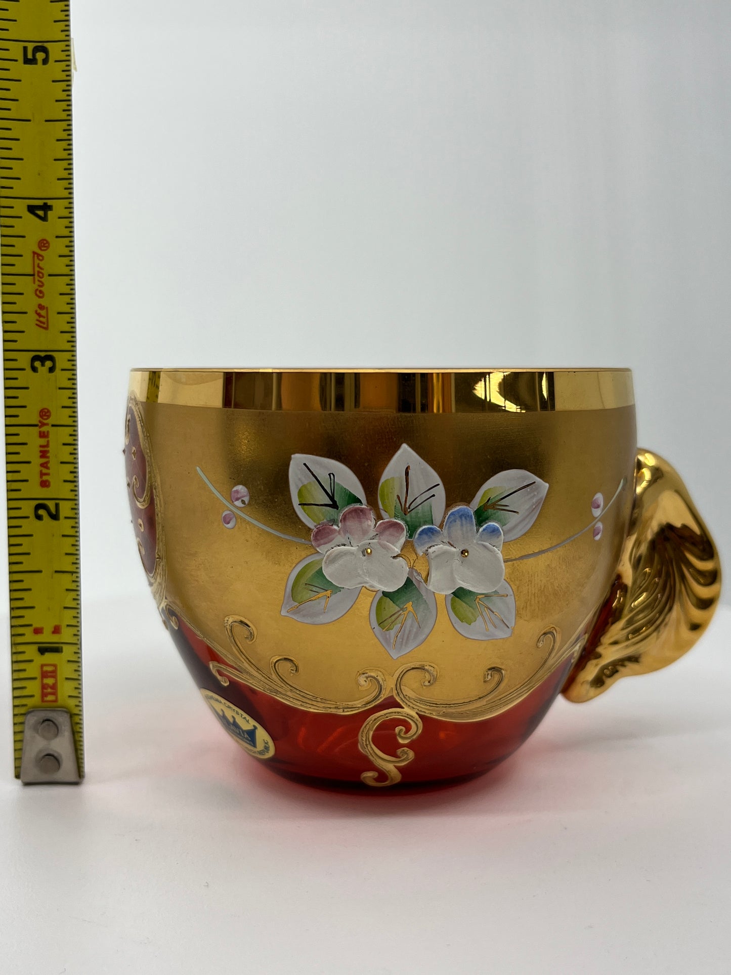Decorative punchbowl teacup with floral design and gold accents, measured against a ruler.