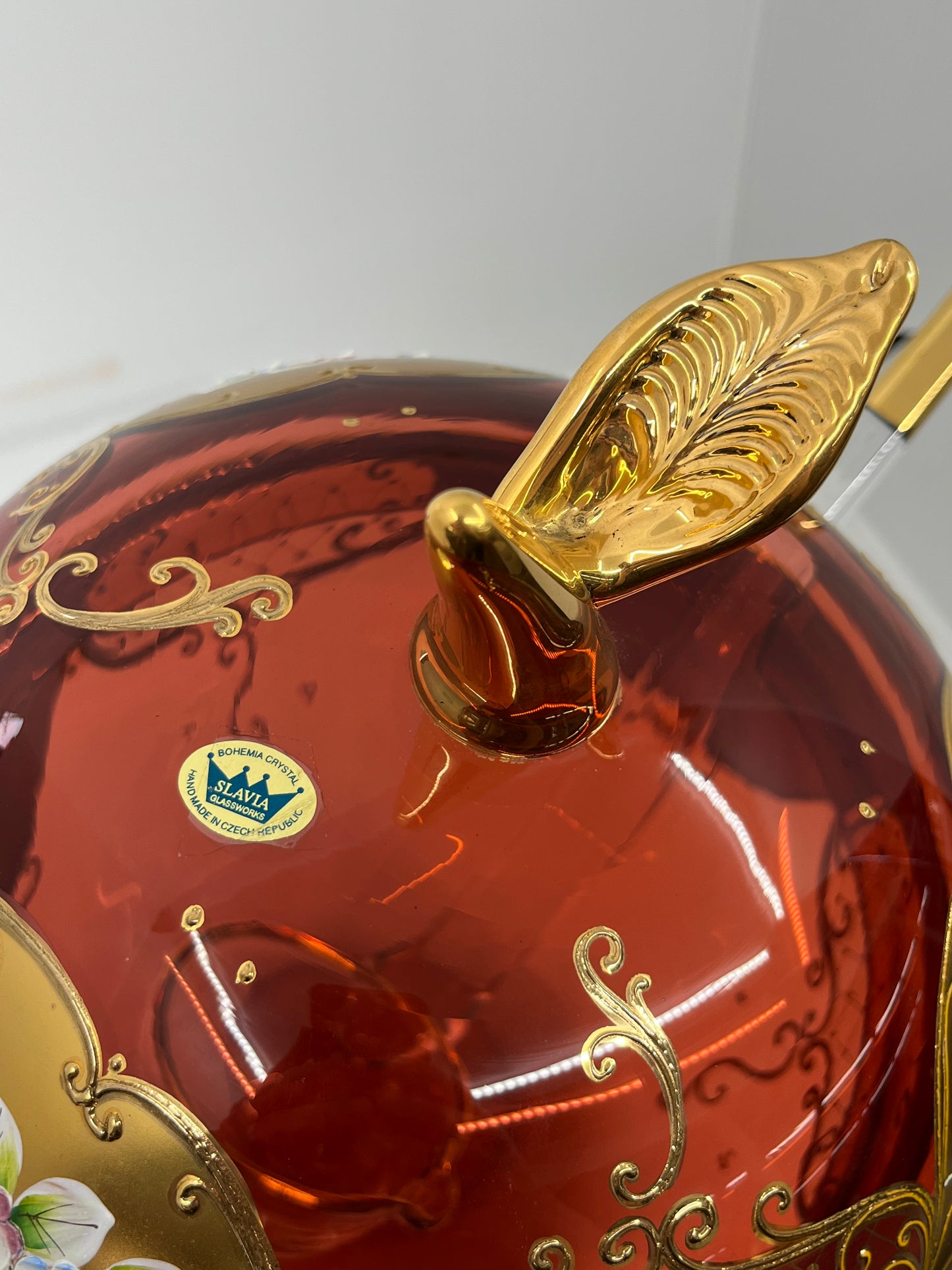 Decorative apple shaped glass punchbowl lid with gold accents and a visible brand logo, Slavia Glassworks, on a white background.