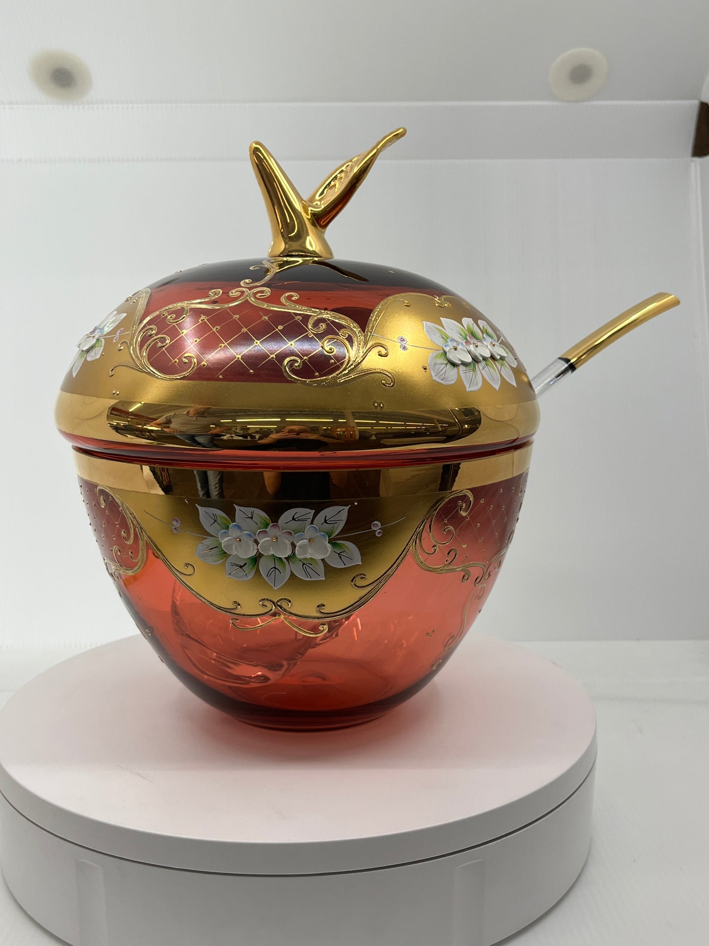 Decorative glass punchbowl with gold accents and floral designs on a white background.