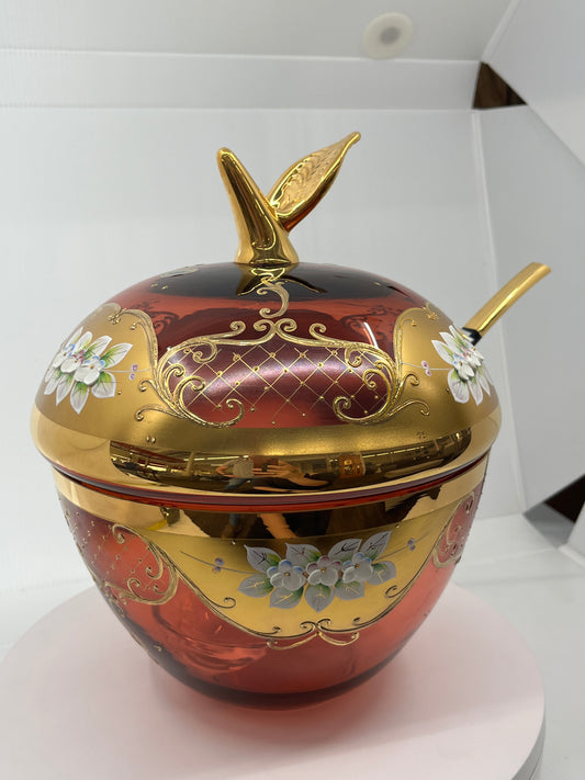 Decorative glass punch bowl shaped like an apple with gold and red design on a white background.