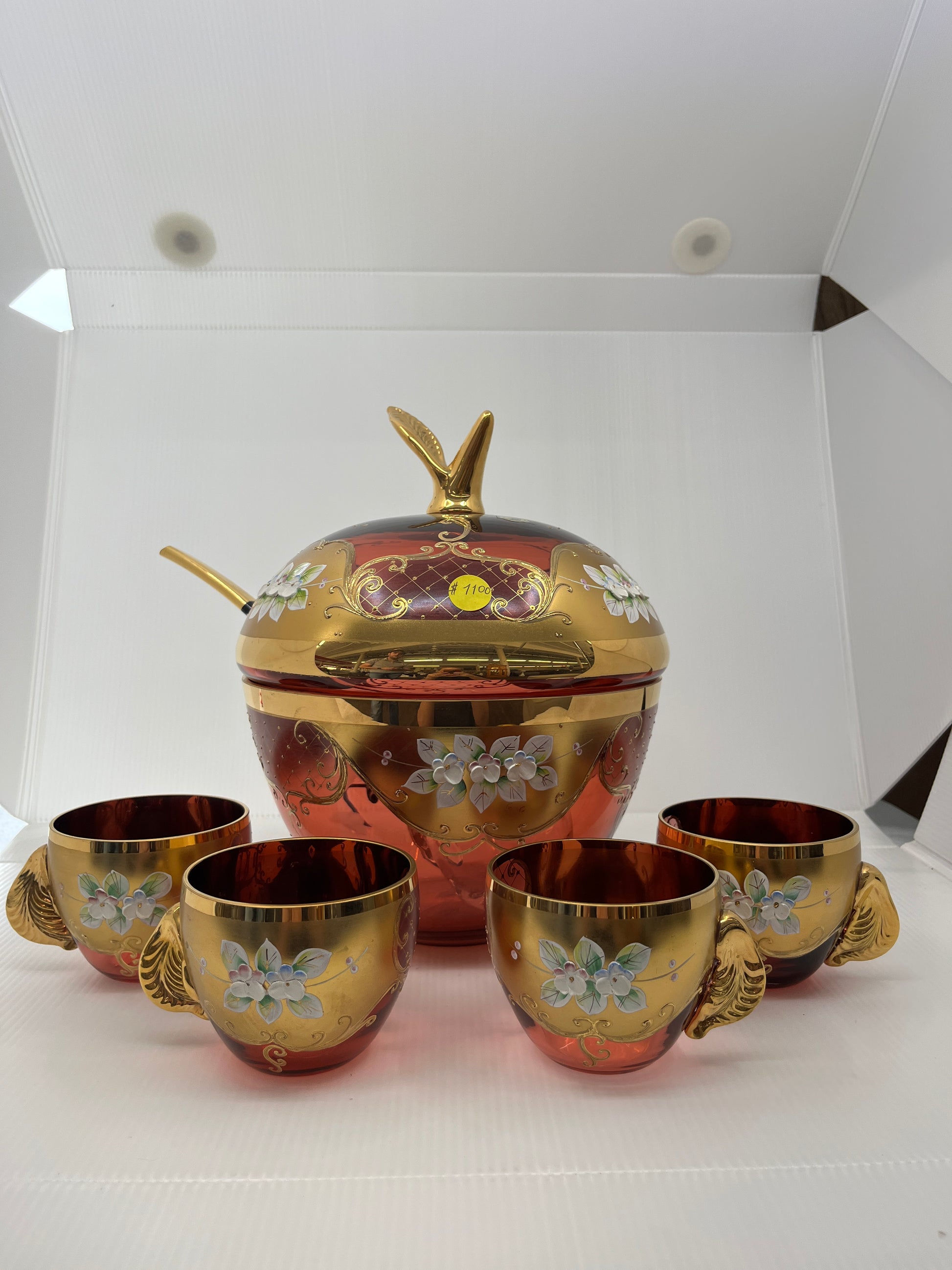 Decorative apple shaped glass punchbowl set with floral patterns on a white background.