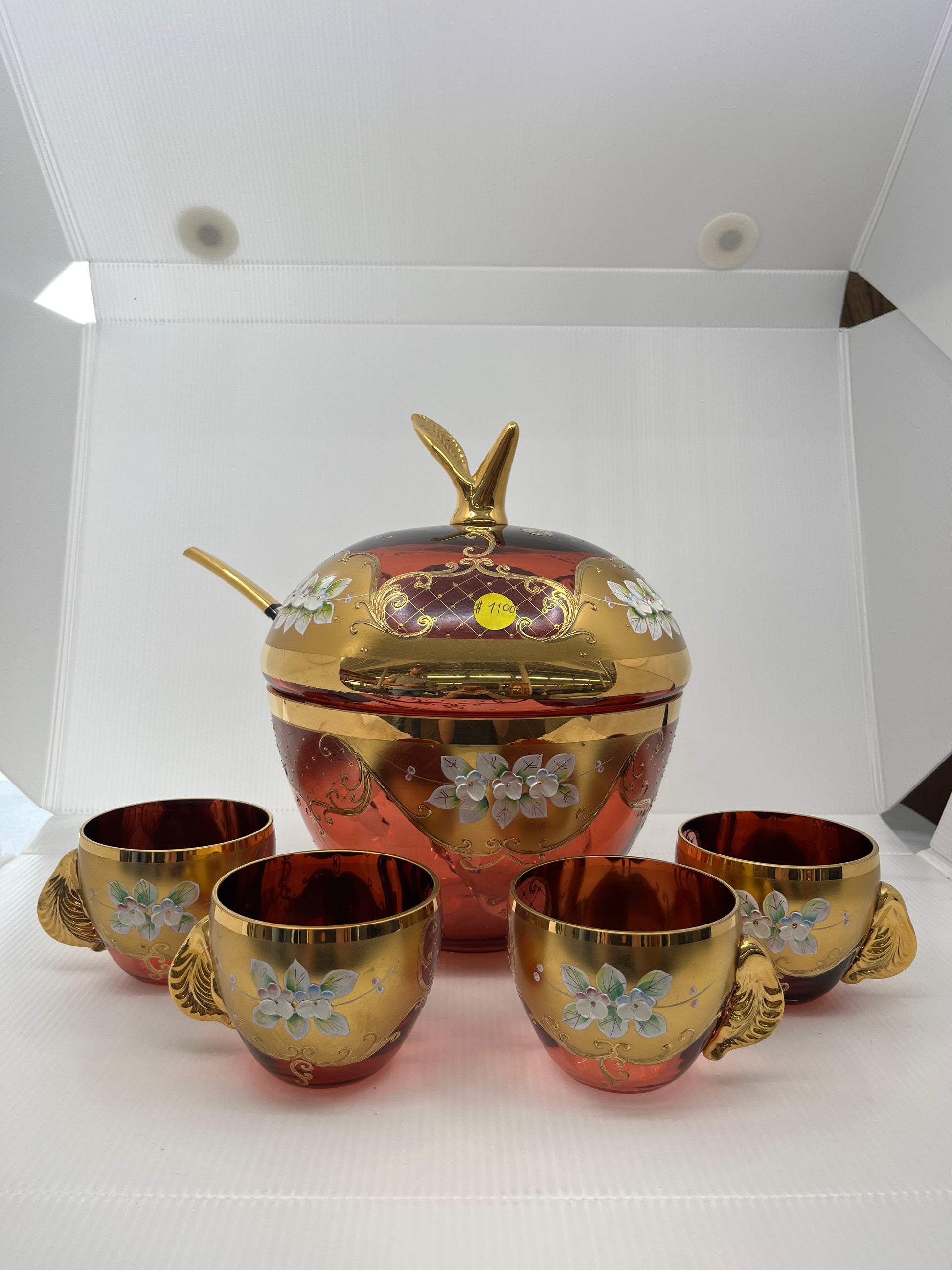 Decorative glass apple shaped punchbowl with four matching cups on a white background.