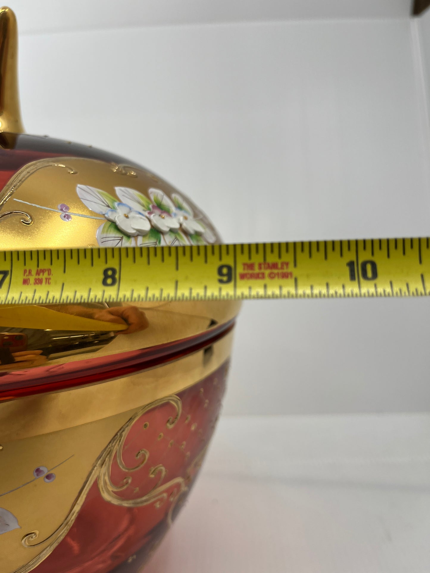 Decorative punch bowl with a tape measure for scale on a white background